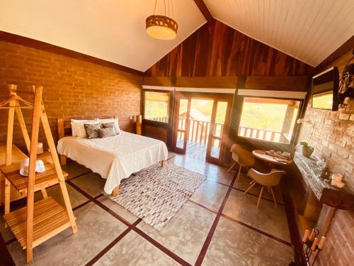 a bedroom with a bed and a brick wall at Chale com hidro na Serra da Mantiqueira in Sapucaí-Mirim