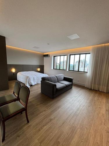 a bedroom with a bed and a couch and a chair at Apart Hotel Moderno em Joinville in Joinville