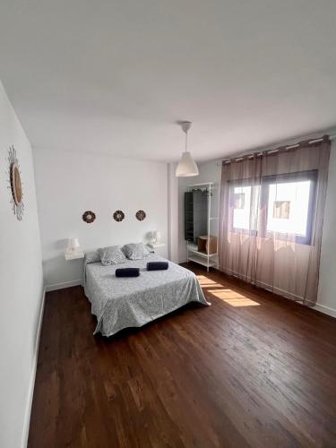 a white bedroom with a bed and a wooden floor at CASA DOMINGO 2 in La Santa