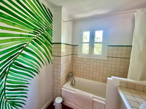 La salle de bains est pourvue d'une baignoire blanche et d'une plante verte. dans l'établissement Les Restanques Maison 12 Lac, à Grimaud