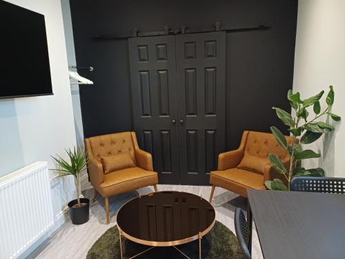 a living room with two chairs and a door at Crescent House in Plymouth
