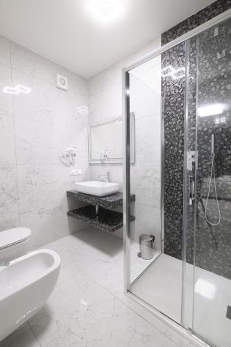 a white bathroom with a shower and a sink at MirabiLuxury in Borgo Fosso Ghiaia