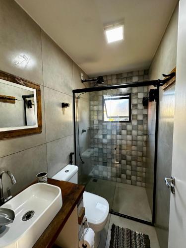 a bathroom with a shower and a toilet and a sink at Canastra - Chalés Canário de Minas in São João Batista do Glória