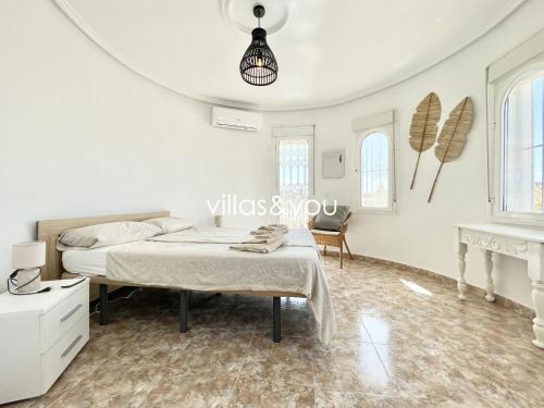 ein weißes Schlafzimmer mit einem Bett und einem Tisch in der Unterkunft Villa Palmera Ciudad Quesada by Villas&You in Rojales