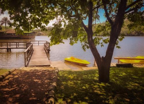 a wooden dock with a yellow boat on a lake at Hotel La Dolce Vita in Tijucas do Sul