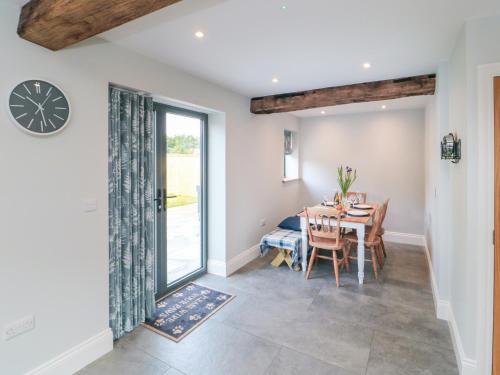 a dining room with a table and a clock on the wall at The Stables in Thirsk