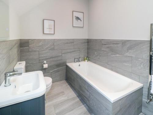 a bathroom with a tub and a toilet and a sink at The Stables in Thirsk