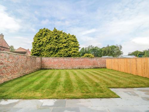 a garden with a brick wall and a fence at The Stables in Thirsk
