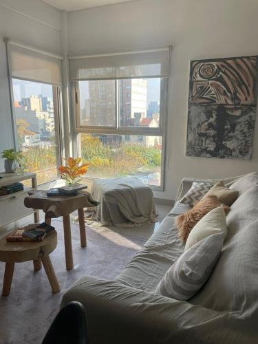 a living room with a bed and a table and windows at Lovely sunset department in Morón