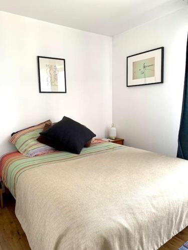 une chambre avec un lit avec deux tableaux au mur dans l'établissement Chic and peacefull Parisian flat, à Paris