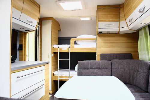 Mietwohnwagen في هورنوم: غرفة صغيرة بها أريكة وأسرّة بطابقين