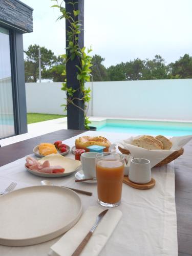 a table with plates of food and a glass of orange juice at Salgueira Pilgrim's Rest in Apúlia