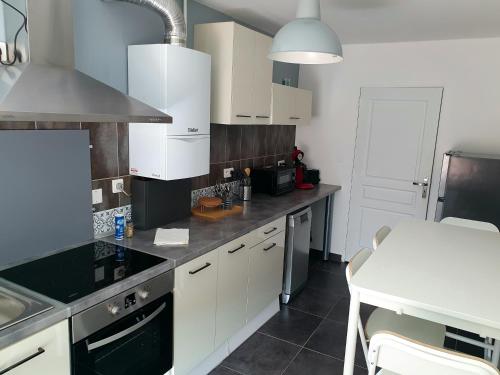 une cuisine avec des armoires blanches et un comptoir noir dans l'établissement Le Central - wifi Netflix - Coeur de ville, à Belfort