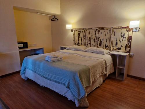 a bedroom with a large bed with two towels on it at Posada Faro Serrano in Villa General Belgrano
