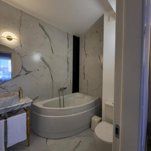 a white bathroom with a tub and a toilet at Apartament elegant cu terasă in Bucharest