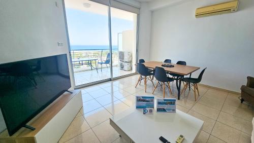 a dining room with a table and chairs and a balcony at Paradise Palms Seaview Apartment in Larnaka