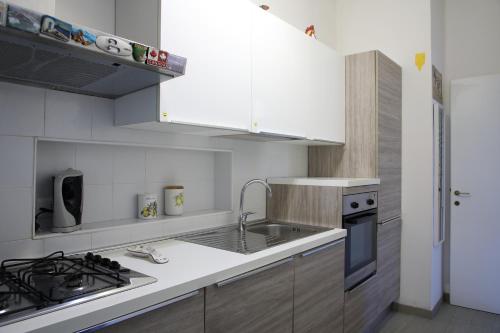 a kitchen with white cabinets and a sink and a stove at La Nave di Stefy in Fregene