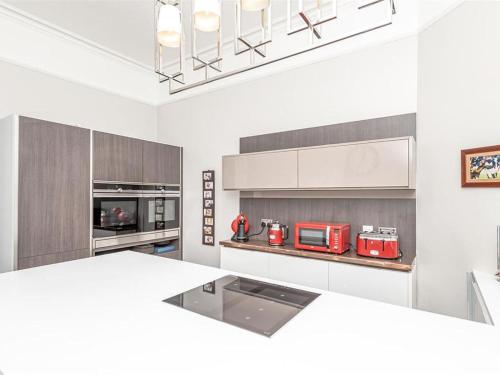 a kitchen with white cabinets and red appliances at Spacious 4 Bedroom Flat in Stirling in Stirling