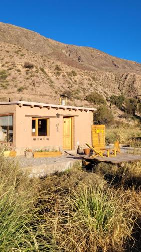 a small house with a yellow door in a field at Las Ranas in Tilcara