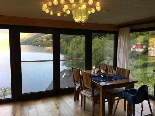 a dining room with a table with a view of a lake at Seehaus Weiss in Rothenthurn