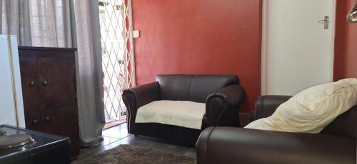 a living room with a couch and a chair at Henning nest guest house in Centurion