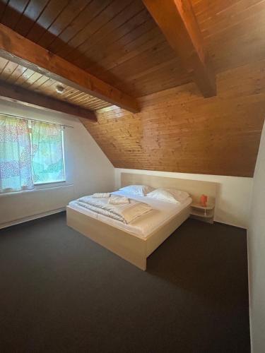 una cama en una habitación con techo de madera en Penzión Zemanov dvor, en Lietavská Svinná