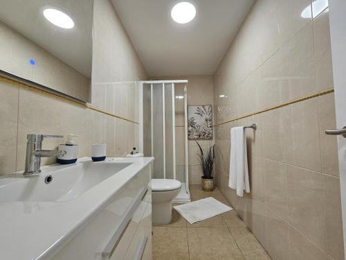 Un baño blanco con lavabo e inodoro. en Casa Cristina - Playa San Juan, en Playa de San Juan