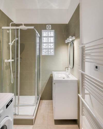 une salle de bain blanche avec une douche et un lavabo dans l'établissement Appartement 2 chambres accès direct Lyon centre, à Vénissieux