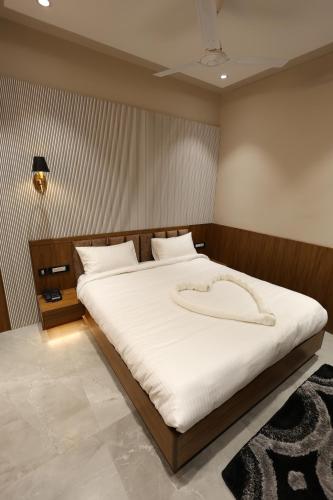 a bedroom with a large bed with white sheets at THE SRM CRYSTAL in Kānpur