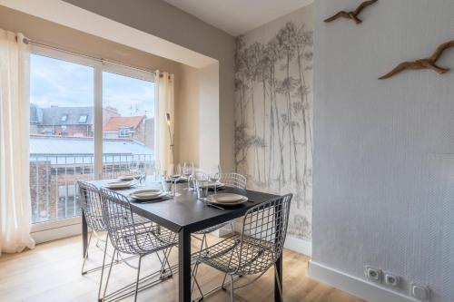 een eetkamer met een tafel met stoelen en een raam bij Renovated 3-bedroom flat on the Grand Place in Lille
