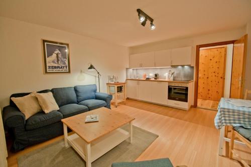 a living room with a blue couch and a table at Dent Blanche in Zermatt