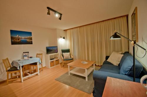 a living room with a blue couch and a table at Dent Blanche in Zermatt