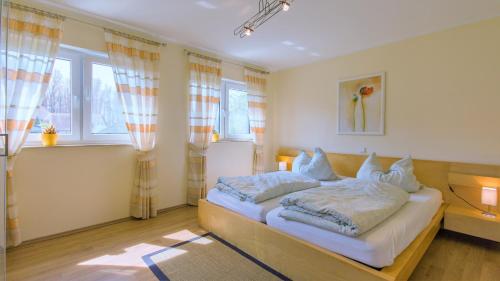 una camera da letto con un letto con lenzuola e cuscini bianchi di Haus Amber Glowe a Glowe