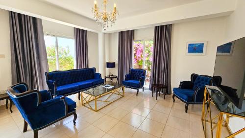a living room with blue chairs and a chandelier at Seaview Sanctuary House in Larnaka