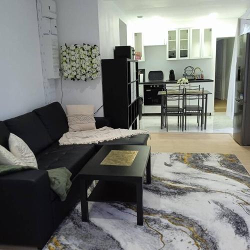 un salon avec un canapé noir et une table dans l'établissement La Maison du Cerisier, à Laon