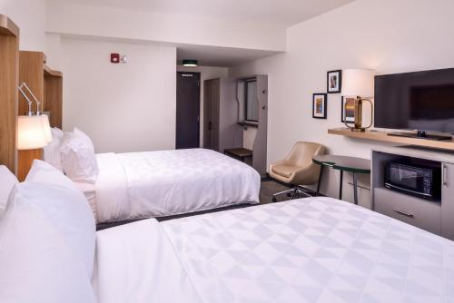 a hotel room with two beds and a flat screen tv at Holiday Inn Detroit Northwest - Livonia by IHG in Livonia
