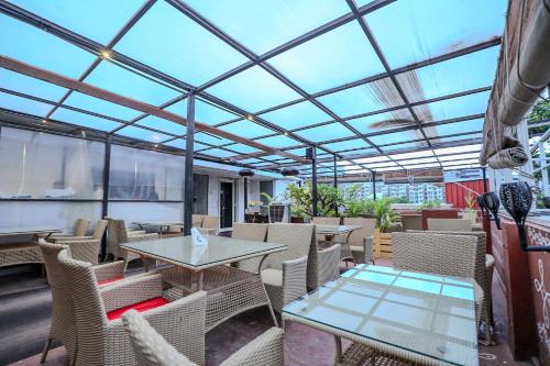 an outdoor patio with tables and chairs and a roof at Hotel White Fields Hitec City, Hyderabad in Hyderabad