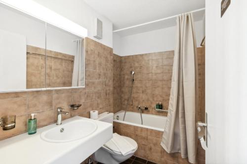 a bathroom with a sink and a toilet and a tub at Beautiful Boutique Apartment DRAHTZUG8 in Zürich