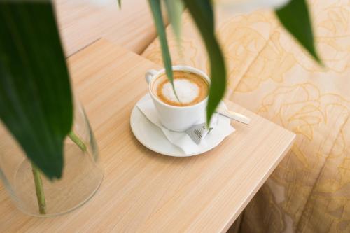 a cup of coffee on a table with a plant at Hotel SPA Arkadia in Apšuciems