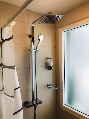 a shower in a bathroom next to a window at City Center Cozy in Pattaya