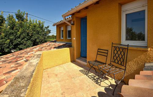 une maison jaune avec une chaise sur une terrasse couverte dans l'établissement 1 Bedroom Gorgeous Home In Caromb, à Caromb