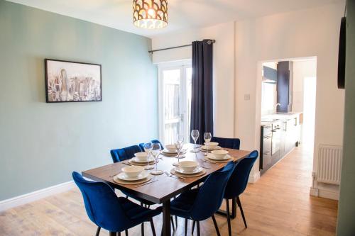 a dining room with a wooden table and blue chairs at Stunning House - Sleeps 7 - 5 Mins walk to Lincoln High Street - Parking - Wifi in Lincolnshire