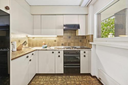 a kitchen with white cabinets and a sink and a window at Beautiful Boutique Apartment DRAHTZUG8 in Zürich