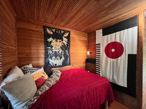 a bedroom with a red bed with a painting on the wall at Retro Rustic Cabin in Nummistenkylä