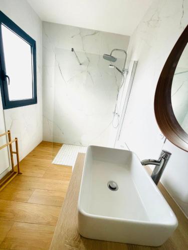 une salle de bain avec un lavabo blanc et un miroir dans l'établissement Relax plage et bassin, à Le Porge