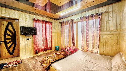 a bedroom with a bed in a room with wooden walls at Muskan Villa in Leh