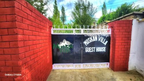 a red brick wall with a gate with a guest house at Muskan Villa in Leh