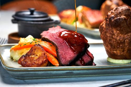 a plate of food with meat and vegetables on a table at Hotel Indigo Manchester - Victoria Station by IHG in Manchester
