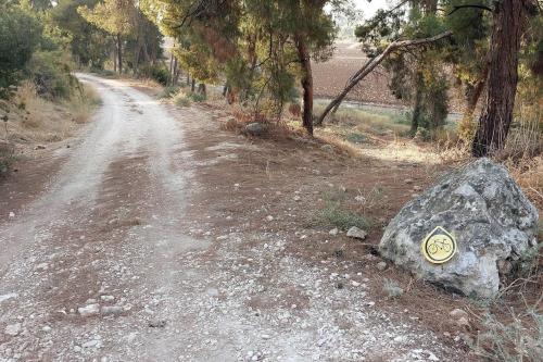 a rock with a sign on it next to a dirt road at יחידת אירוח כפרית in Gid‘ona