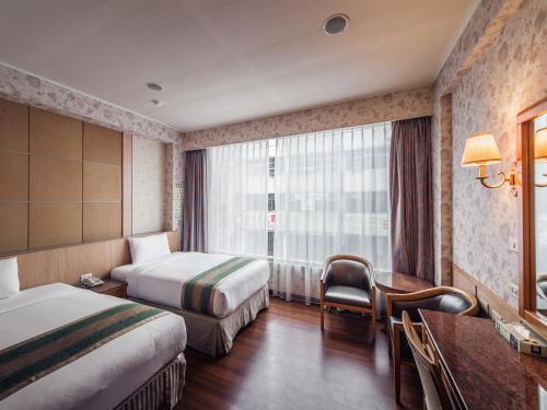 花蓮市にあるDa Shih Hotelのベッド2台と机があるホテルの部屋